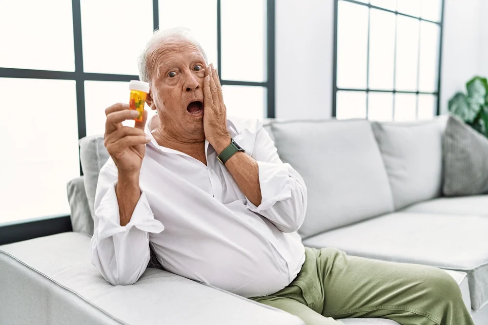 a man sitting on a couch holding a bottle of pills / What to Do When Medication Goes Wrong: A Simple Guide for Families, Carers, and Managers / Common Medication Errors / What to Do When Medication Goes Wrong / What Managers Should Do When Medication Errors Occur / How to Prevent Medication Errors in the Future / Handling Medication Mistakes with Confidence / Pharmacy CareRX in Florida