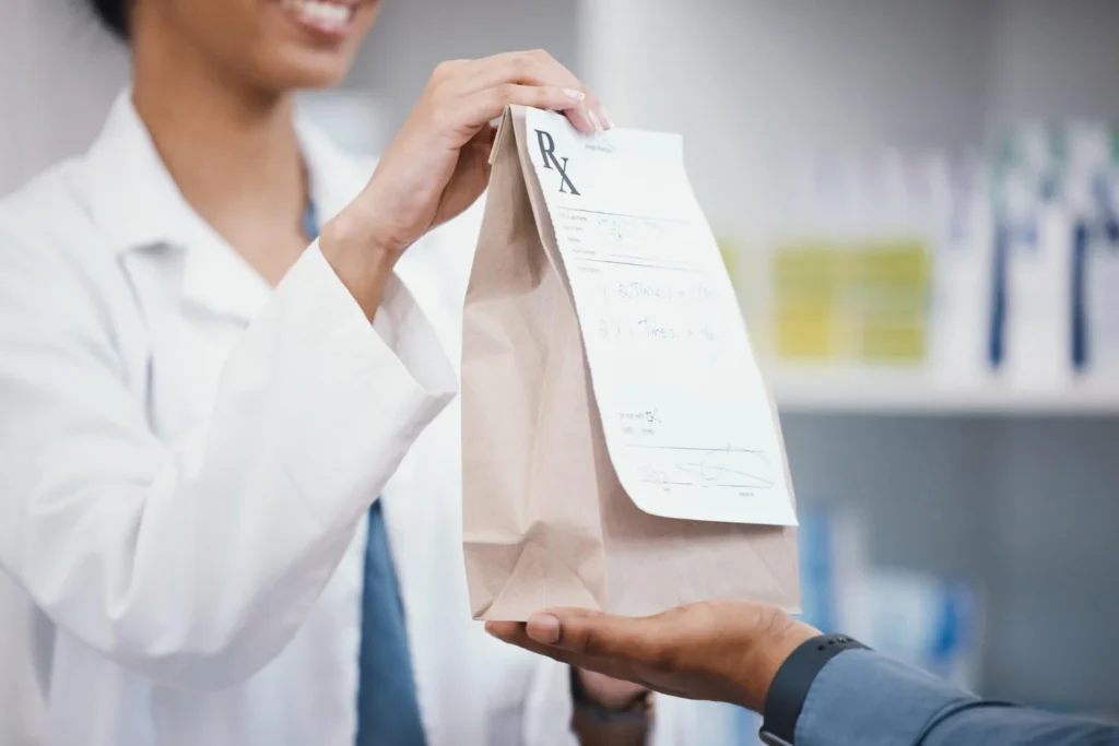 a doctor handing a prescription to a patient / Understanding Brown Bagging in Pharmacy: What You Need to Know / What Is Brown Bagging in Healthcare? / When and Where Is Brown Bagging Used? / How the Brown Bagging Process Works / Why Healthcare Systems Use Brown Bagging / Risks and Concerns of Brown Bagging / Brown Bagging vs. White Bagging: What’s the Difference? / What Is Clear Bagging and How Is It Different? /Safety Guidelines for Brown Bagging / Perspectives from Payers and Providers / Pros and Cons of Brown Bagging / Benefits of Brown Bagging /Conclusion: Is Brown Bagging the Right Choice? / Pharmacy Care Rx