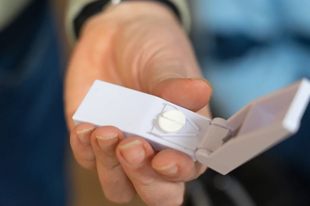 a hand holding a pill / Pill Splitting Guide: How to Safely Cut a Pill / What is Pill Splitting and Why Does It Work? / Is Pill Splitting Legal and Safe? / What Kinds of Pills Can Be Split? / Pills You Should NEVER Split / What Could Go Wrong with Pill Splitting? / How to Split Pills the Right Way / Tips for Safe Storage and Use of Split Pills / Talk to Your Doctor First – Always / Is Pill Splitting the Best Option for You / Alternatives to Pill Splitting: Other Cost-Saving Options / Be Smart, Be Safe: Important Reminders for Pill Splitting / Pharmacy Care RX