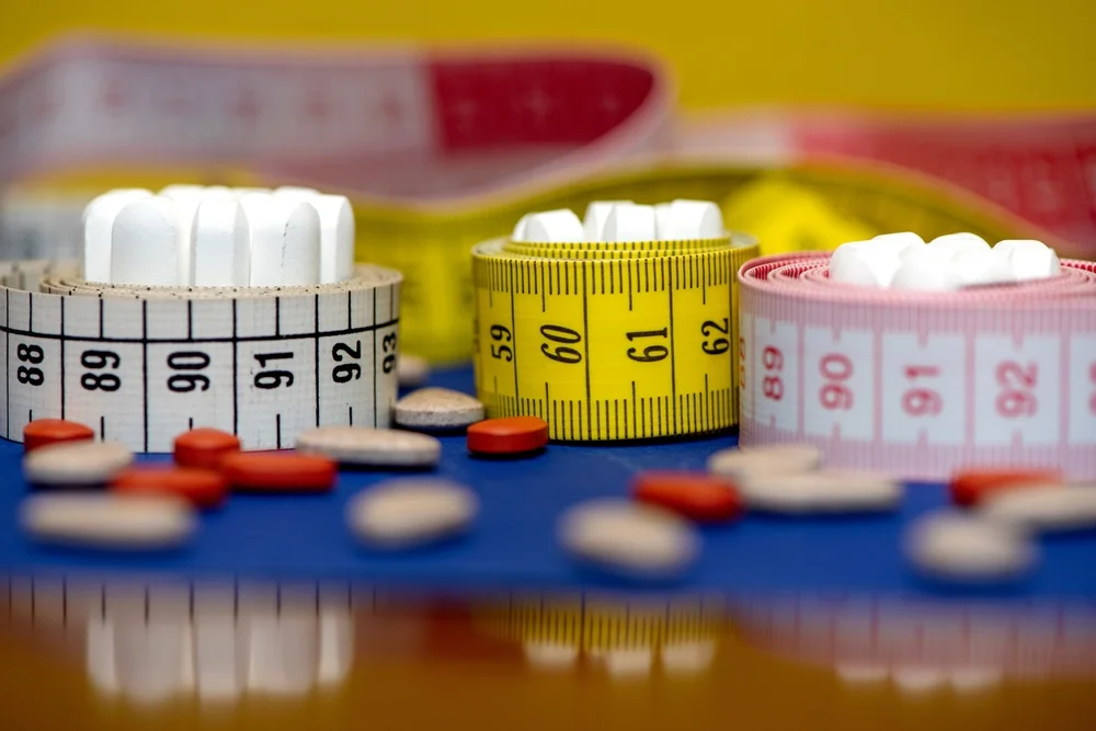 a measuring tape and pills / Weight-Based Medication Dosing: A Complete Guide / What is Weight-Based Medication Dosing? / Why is Weight-Based Dosing Important? / How is Weight-Based Medication Dosing Calculated? / Applications of Weight-Based Medication Dosing / Common Medications That Use Weight-Based Dosing / Factors to Consider in Weight-Based Dosing / Challenges in Weight-Based Dosing / FAQs on Weight-Based Medication Dosing / Pharmacy Care RX