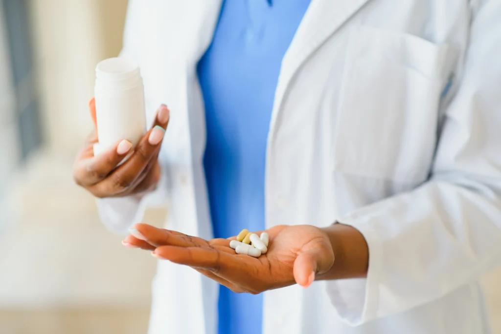 Close-up of an Afro-American doctor showing pills and glass of water at the camera. Pharmacy CareRx in Florida