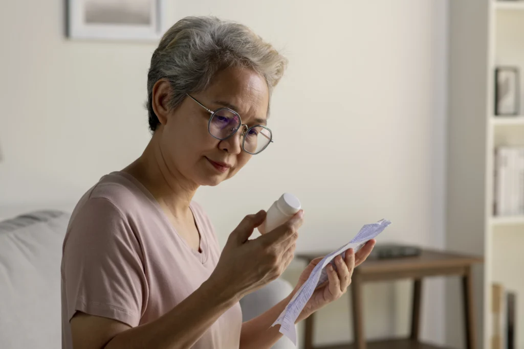 Older woman checking her Plavix medication bottle and prescription instructions at home