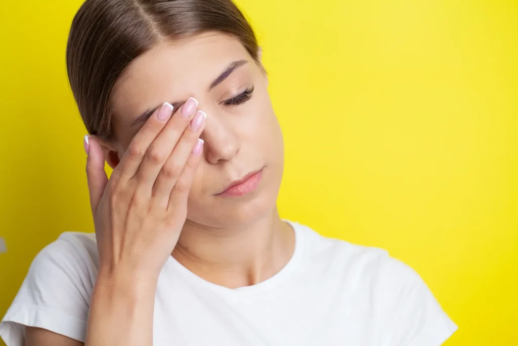 Woman wiping watery eyes caused by allergy symptoms
