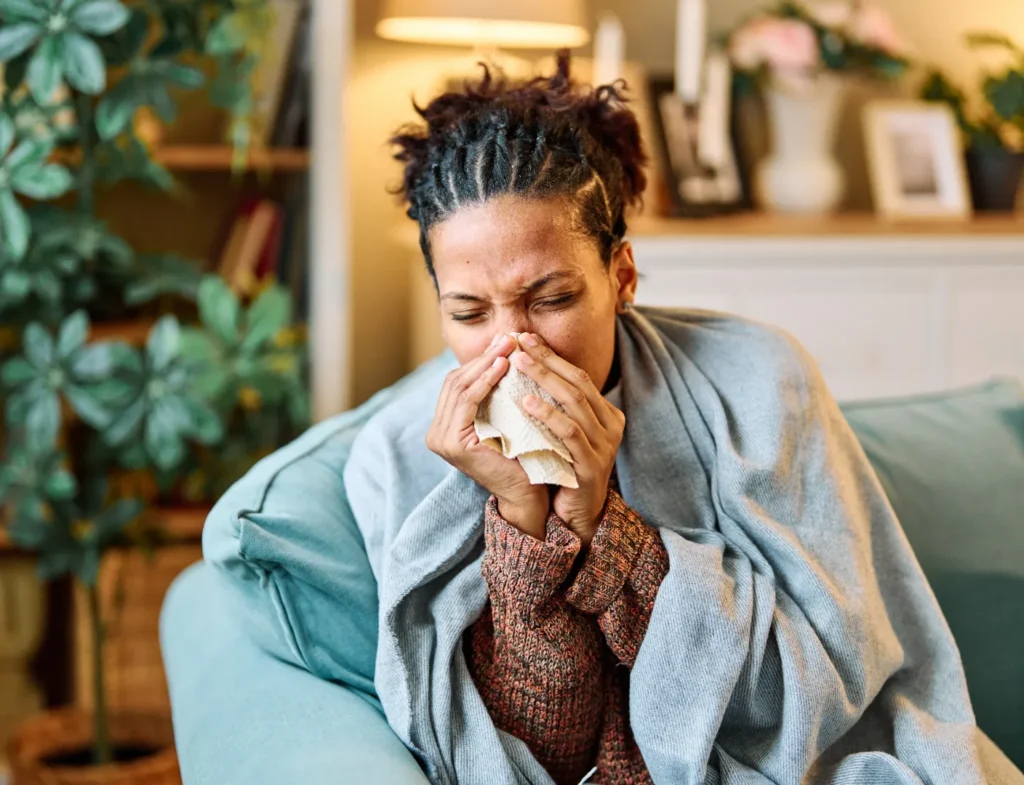 Person sneezing into a tissue due to allergy symptoms
