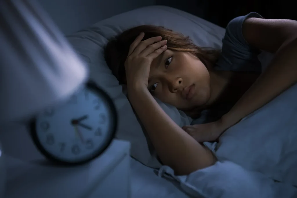 Person lying awake in bed experiencing difficulty sleeping