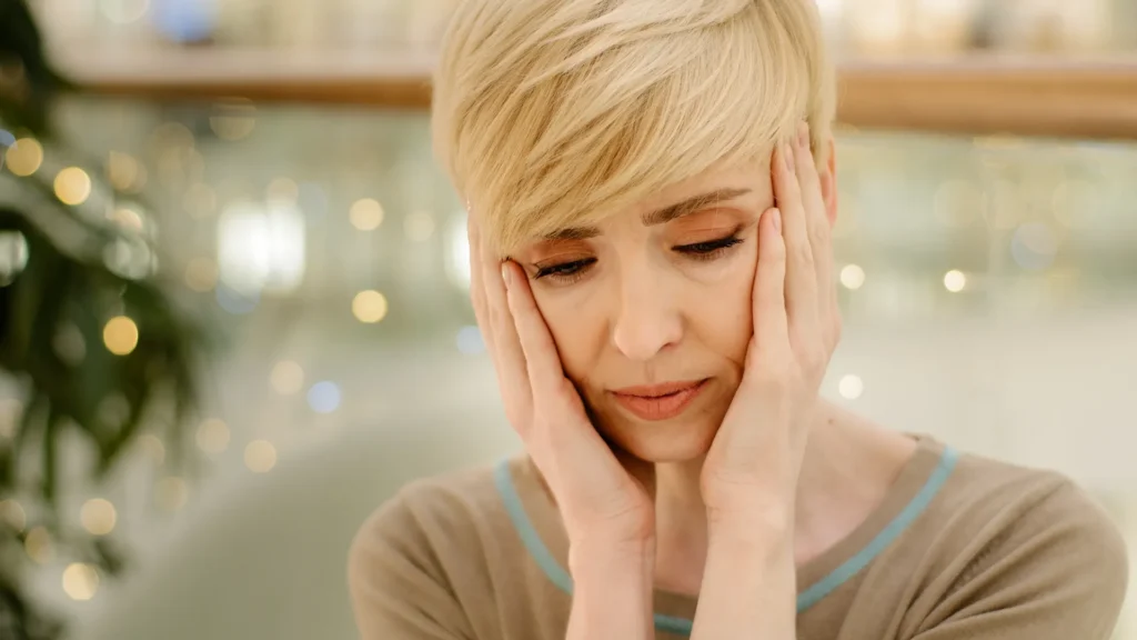 Woman holding her head while experiencing a headache during methylprednisolone treatment