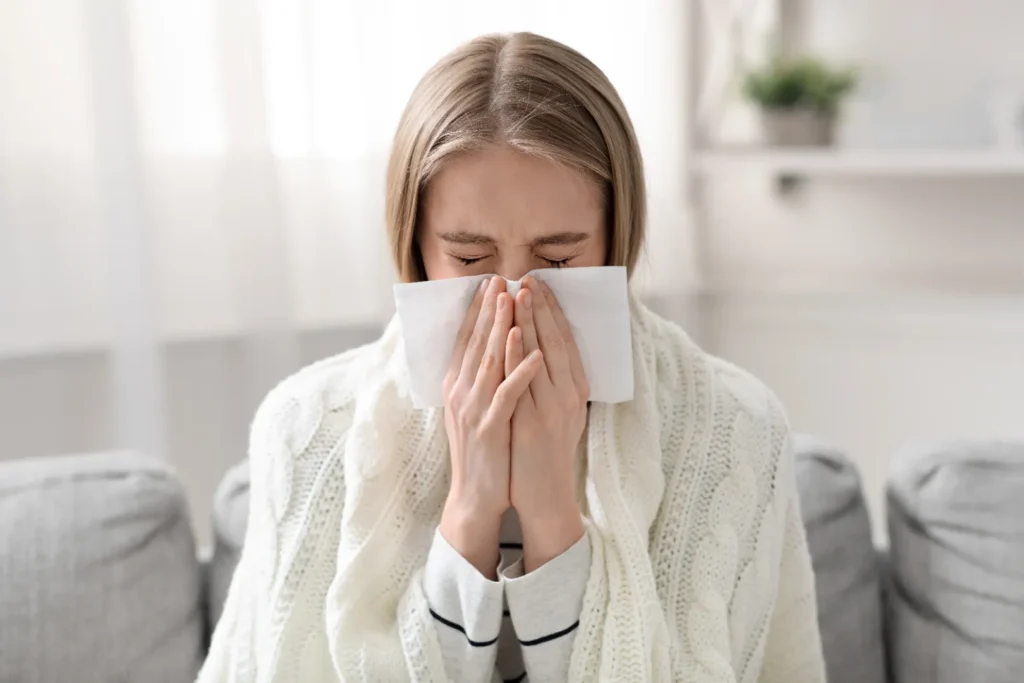 Woman with a runny nose wiping her nose with a tissue