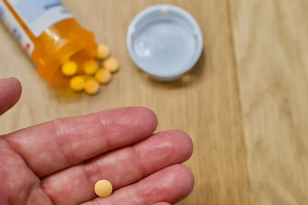 A person holding a medicine in hand signifying taking medicine on time.